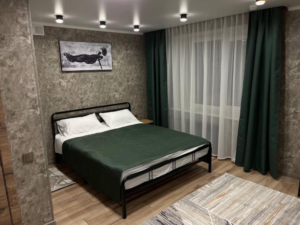 a bedroom with a bed with a green comforter at DEMAL HOTEL in Petropavlovsk