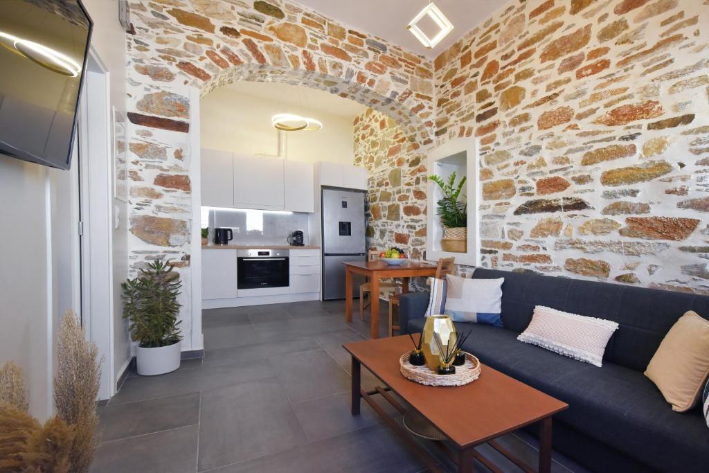 a living room with a blue couch and a stone wall at Ledio's house in Ermoupoli