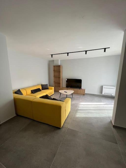 sala de estar con sofá amarillo y mesa en 5th Floor Apartment 2+1 Qerret en Golem
