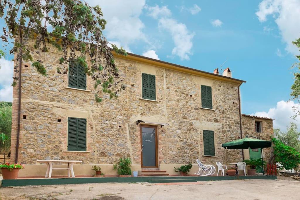 um edifício de pedra com uma mesa e um guarda-chuva em Vetulonia casa colonica con Pool Relax em Castiglione della Pescaia