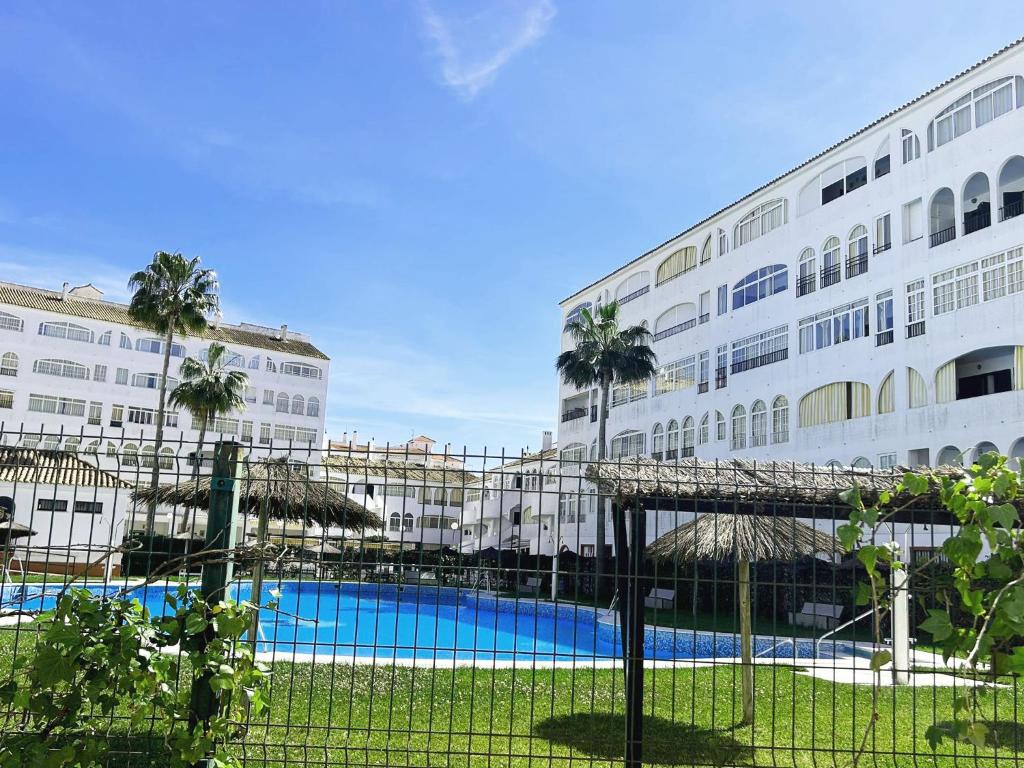 een groot gebouw met een zwembad en palmbomen bij LIFE APARTMENTS EL PORTIL in El Portil