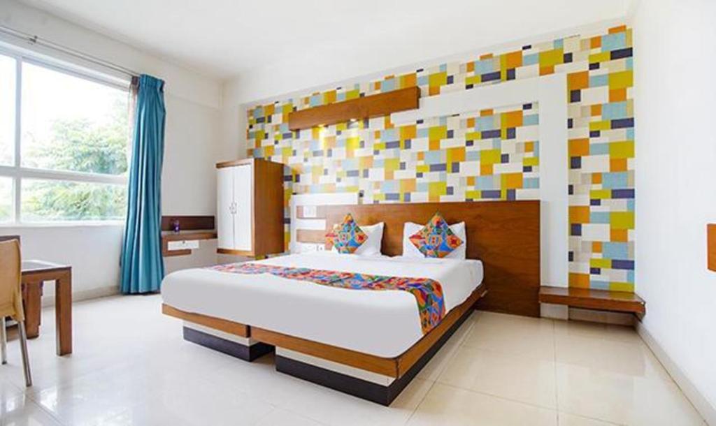 a bedroom with a large bed with a colorful headboard at FabHotel Emirates Suites in Bangalore