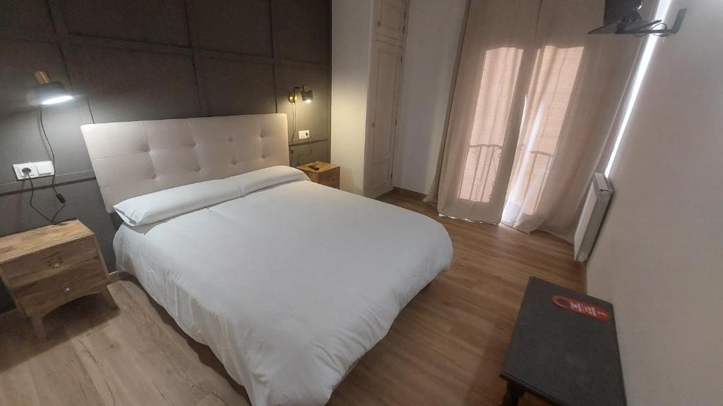 a bedroom with a large white bed and a window at Hostal Rural Sositana in Castejón de Sos