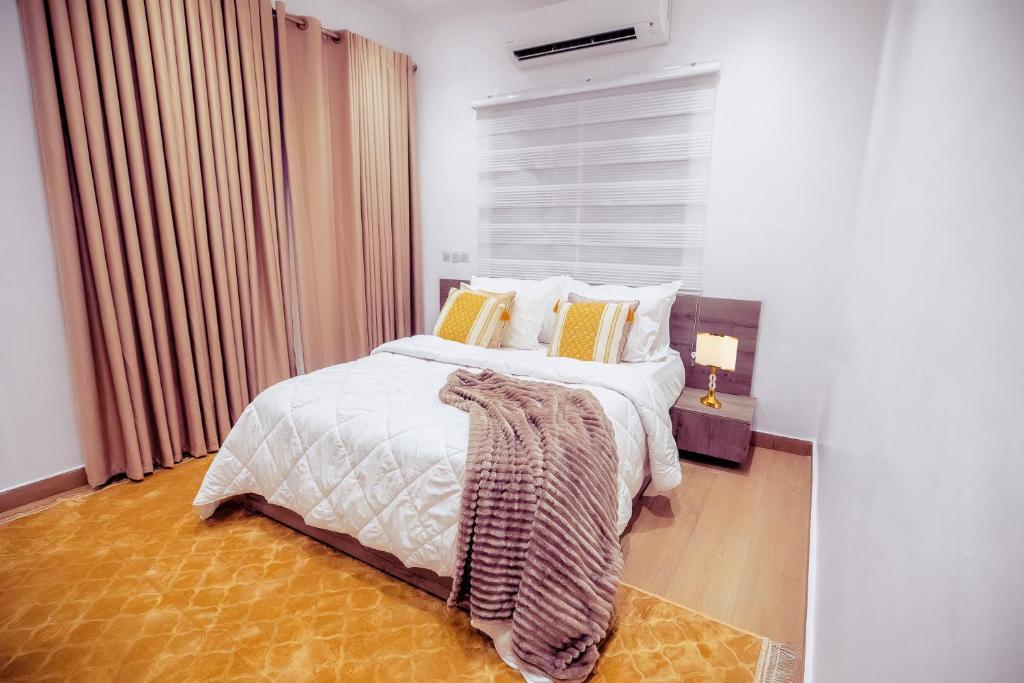 a bedroom with a bed with white sheets and yellow pillows at Rosewood Chamber in Tema