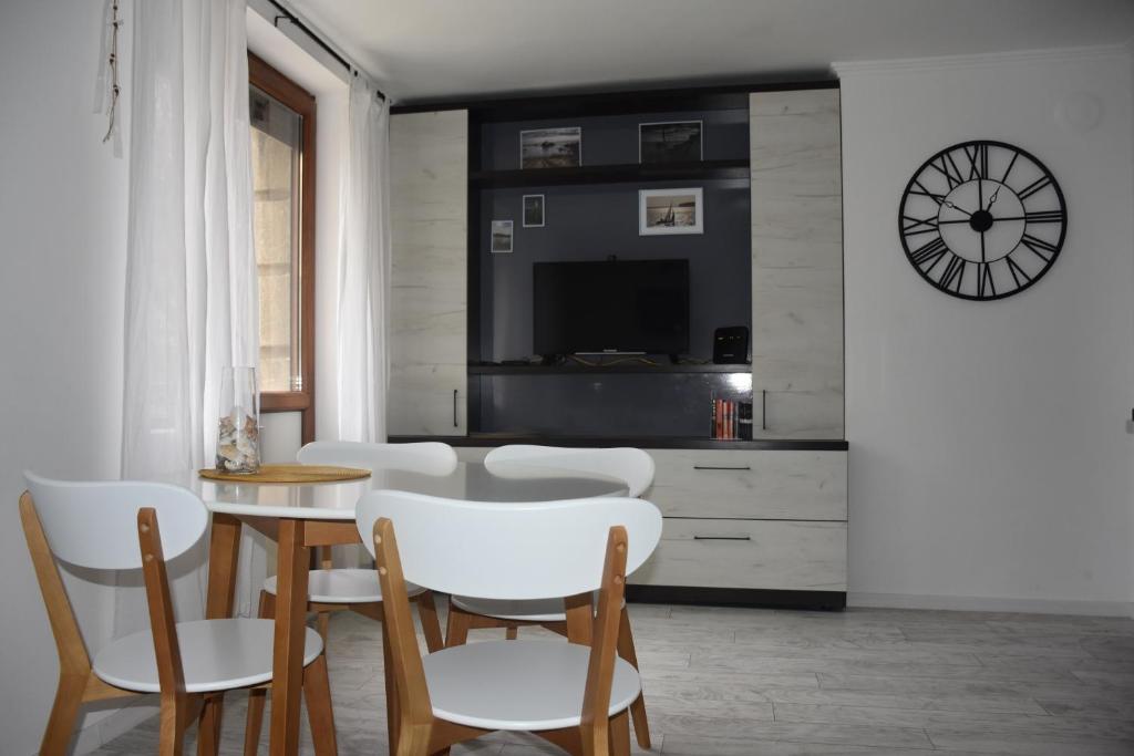 a dining room with a table and chairs and a clock at Sea apartment / Апартамент до морето in Varna City