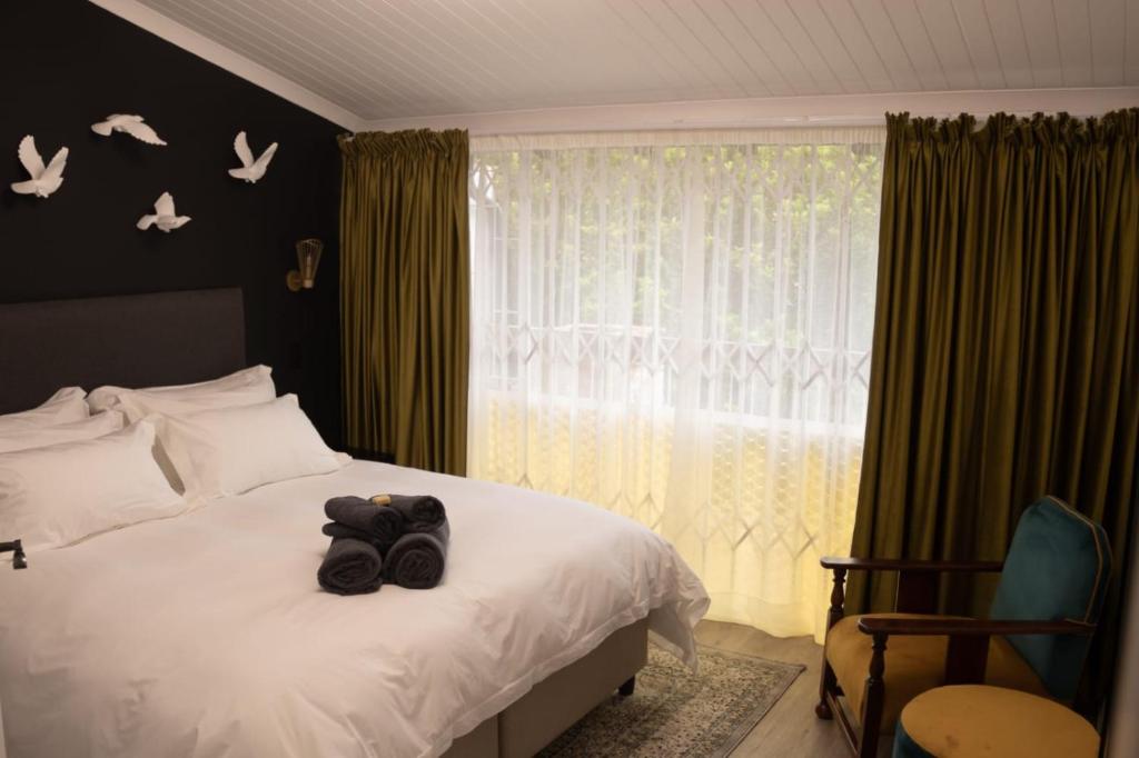 a bedroom with a bed and a window with birds on the wall at Grace in Pretoria