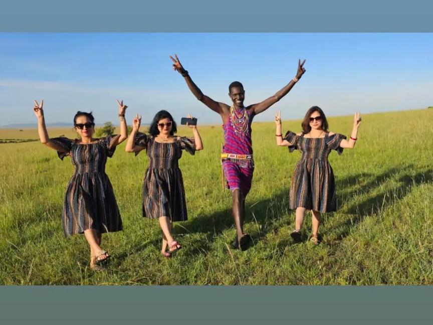 a group of people standing in a field with their arms up at KANUNKA HOUSE in Sekenani