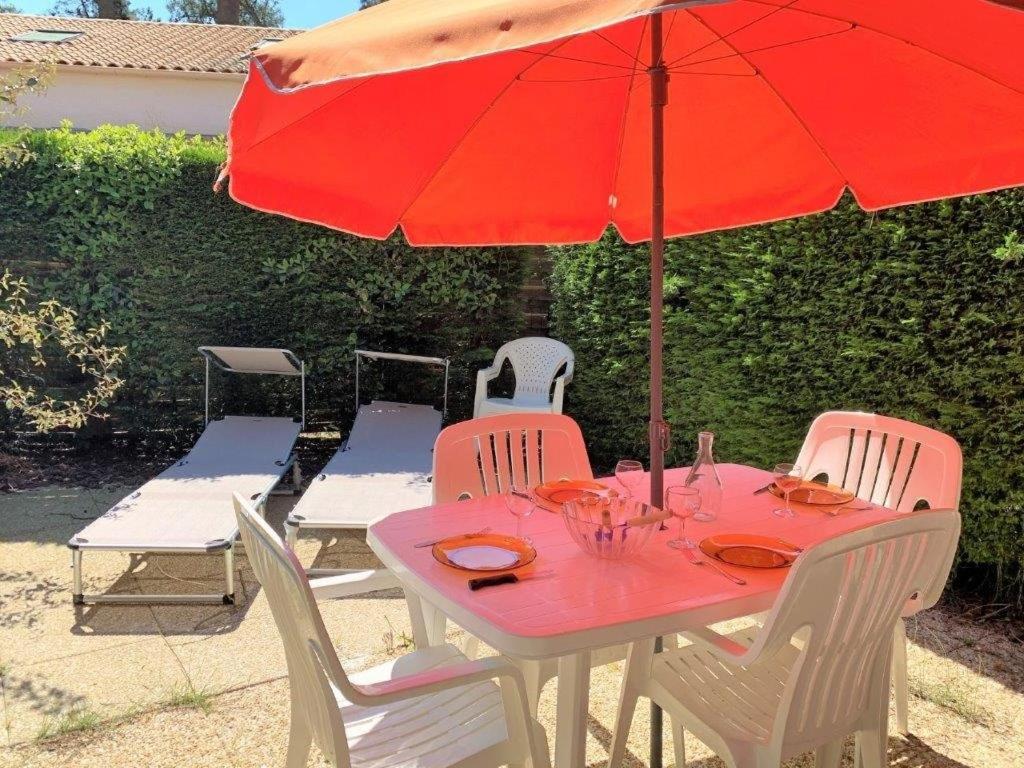- une table avec un parasol rouge et des chaises blanches dans l'établissement La Palmyre - Le HAMEAU de TALARIS - PISCINE COLLECTIVE - 1 étoile, aux Mathes