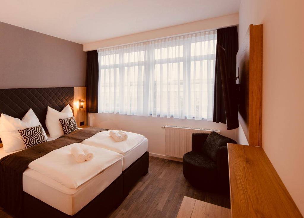 Pokój hotelowy z łóżkiem i krzesłem w obiekcie MiDoma, Self Check-In Hotel, Hannover Messe w Hanowerze