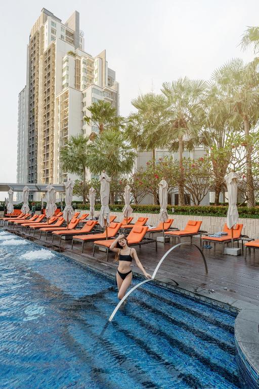 a woman in a bikini jumping into a swimming pool at a resort at Bangkok Marriott Hotel Sukhumvit in Bangkok