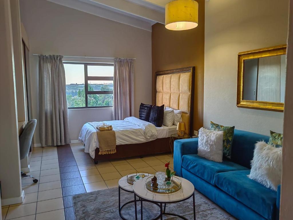 a living room with a blue couch and a bed at Tranquility facing Steyn City in Sandton