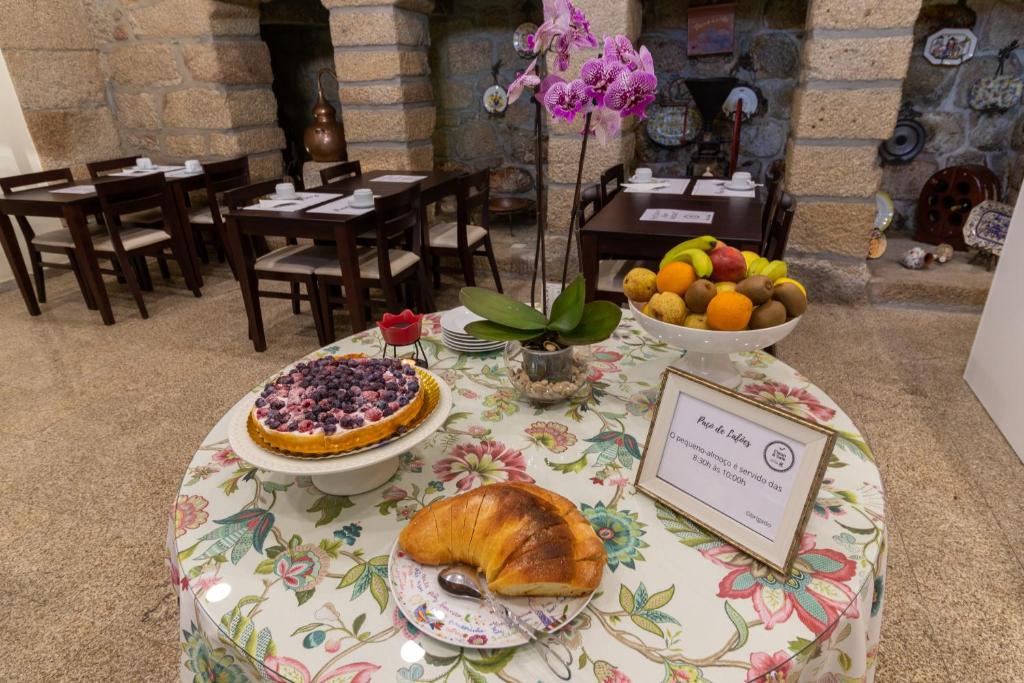 une table avec un tissu de table avec un croissant et des fruits dans l'établissement Casa do Paço, à Termas de São Pedro do Sul