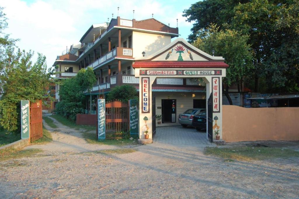 a building with an arch in front of a parking lot at Siddhartha Guest House in Lumbini