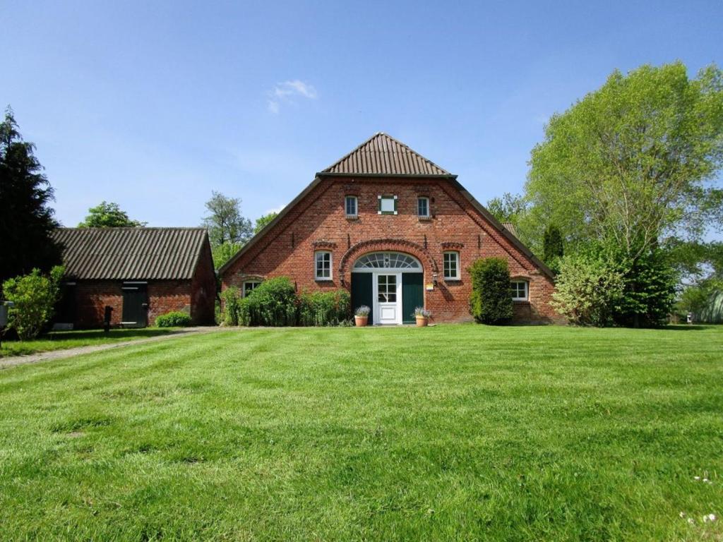 a large brick house with a green lawn at Ferienwohnung Galerie 2 in Niedersachsen-Stadland