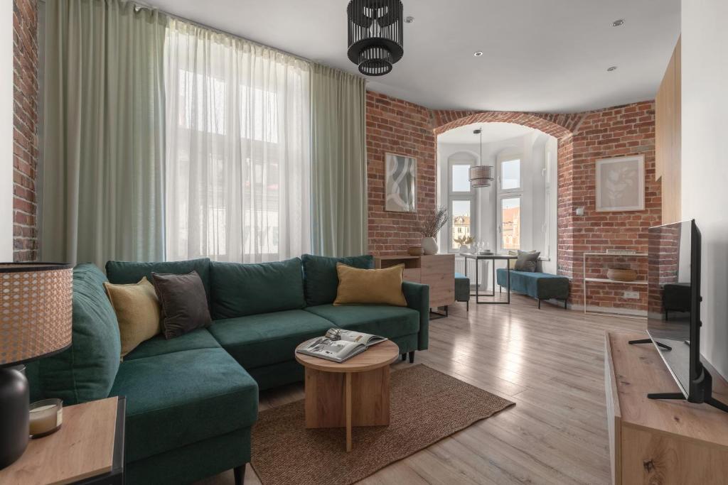 salon z zieloną kanapą i ceglaną ścianą w obiekcie HARBOR APARTMENTS - Mickiewicza w mieście Katowice