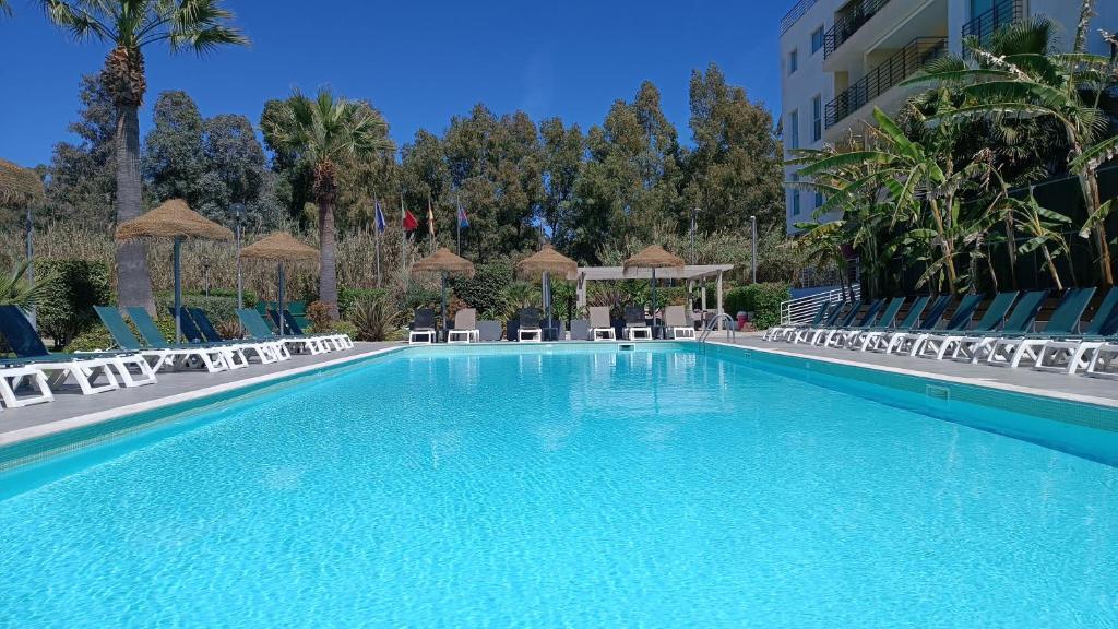 a large swimming pool with chairs and a building at Bayside Salgados in Albufeira