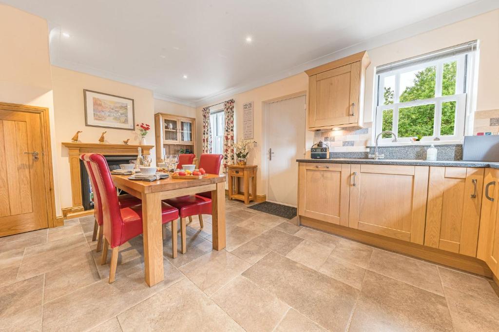 a kitchen with a wooden table and red chairs at Springbank Cottage, luxury Lake District cottage in Coniston in Coniston