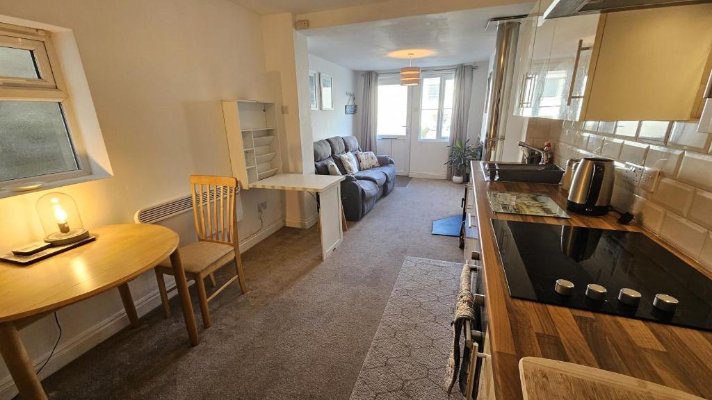 a small kitchen and living room with a table and a couch at Pepperpot in Portreath