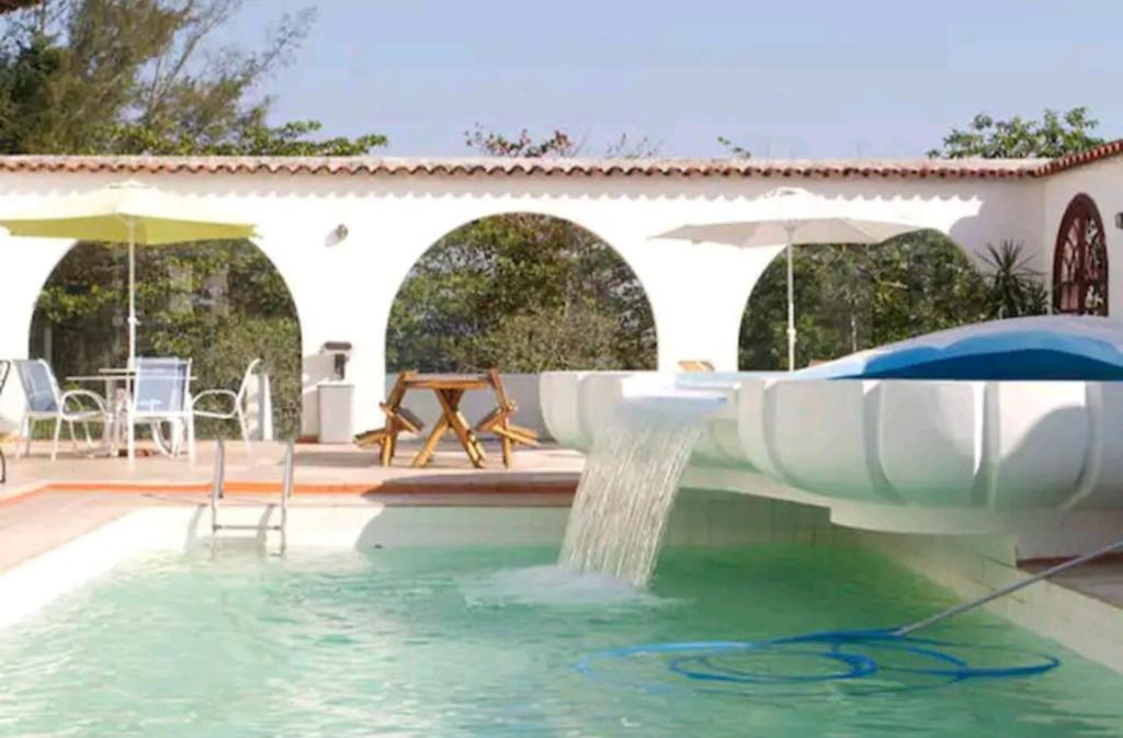 una piscina con una fuente de agua en A Famosa CASA BRANCA Da Barra! Suíte 9 Clássica! en Río de Janeiro