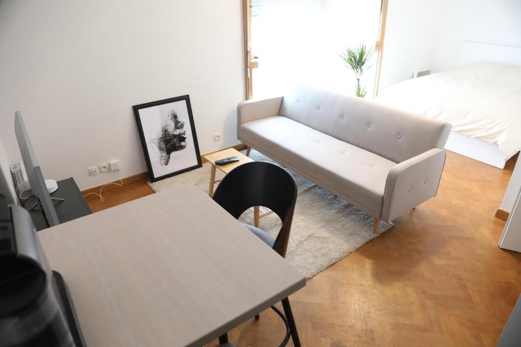 ein Wohnzimmer mit einem Sofa, Tischen und einem Bett in der Unterkunft La suite Prestige de Saint Cyr in Saint-Cyr-lʼÉcole