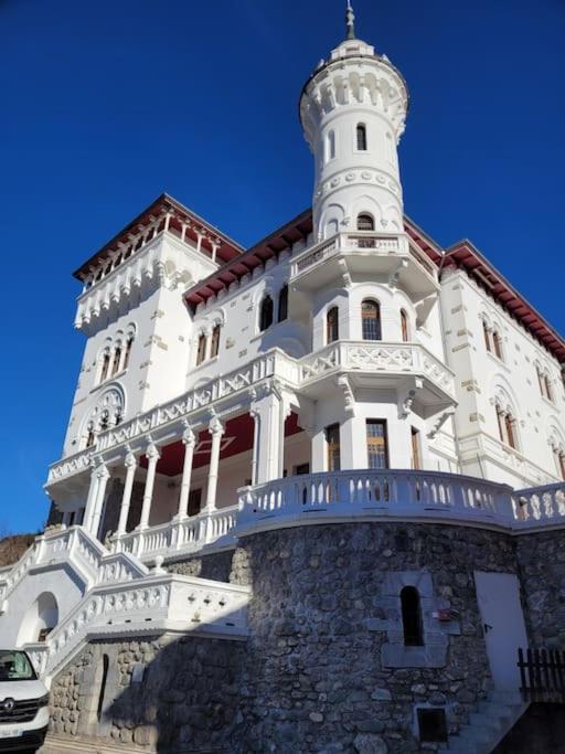 un grand bâtiment blanc avec une tour en haut dans l'établissement Dans château des magnans, grand appartement 10 couchages, à Jausiers