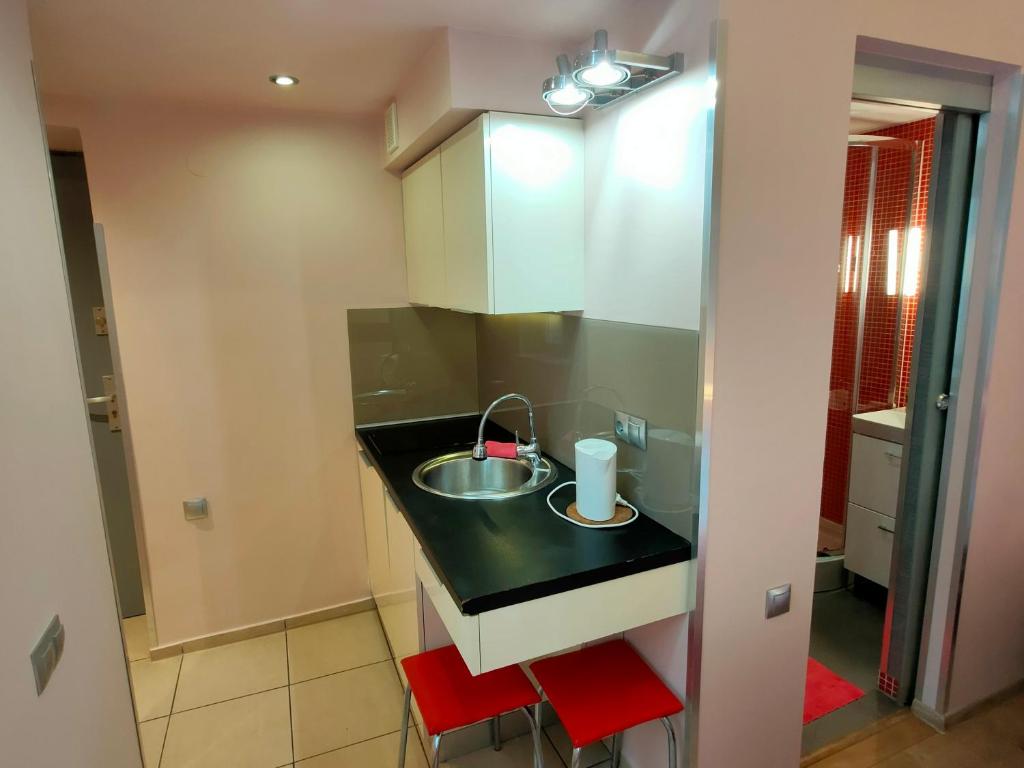 una pequeña cocina con fregadero y taburetes rojos en Mirror Pink Studio Apartment, en Cracovia