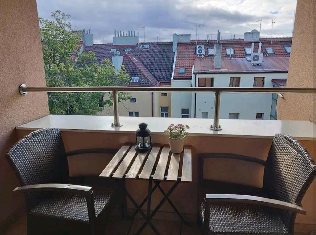 Cozy rooftop with balcony في براغ: شرفة مع طاولة وكراسي خشبية ونافذة