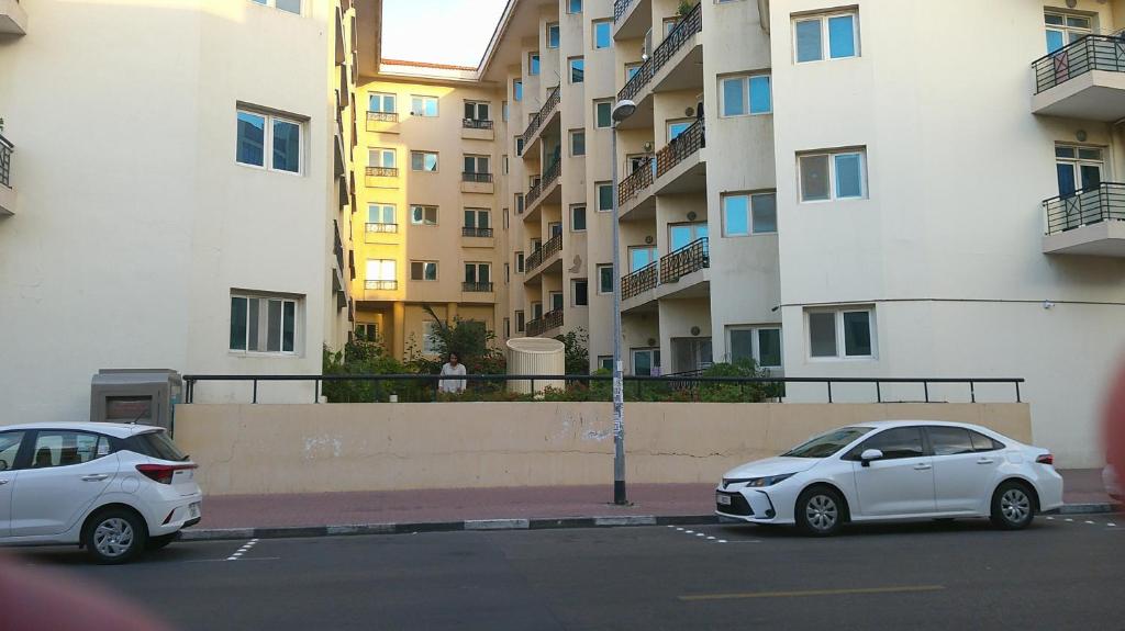 twee witte auto's geparkeerd op een parkeerplaats naast een gebouw bij Ruby Star Hostel Dubai G P-34567 in Dubai