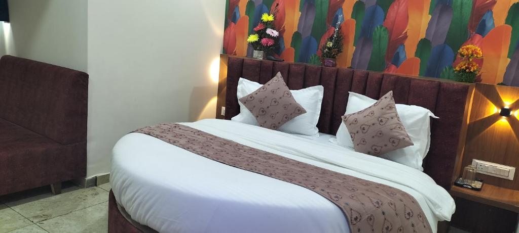 una camera da letto con un grande letto con lenzuola e cuscini bianchi di Hotel Gurukul INN a Ahmedabad