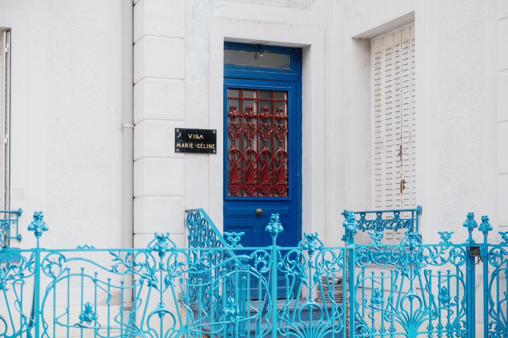 niebieskie drzwi na białym budynku z krzesłami z przodu w obiekcie Studio Vichy célestin Villa Marie Celine w mieście Vichy