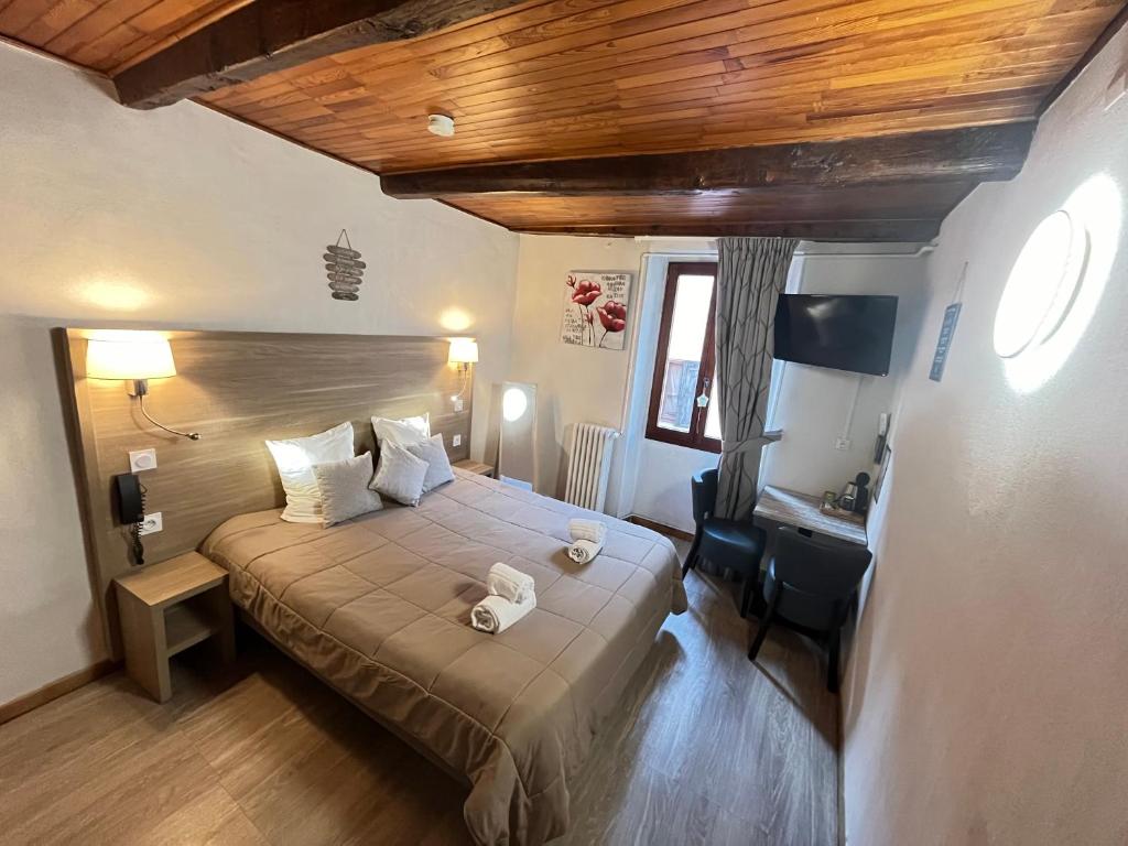 1 dormitorio con cama y escritorio. en Hôtel Du Cheval Blanc, en Barcelonnette