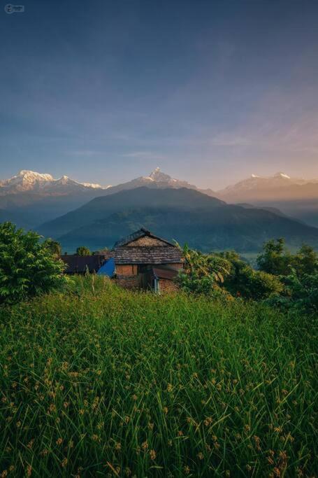 un vecchio edificio su una collina con montagne sullo sfondo di Annapurna Eco Village a Pokhara