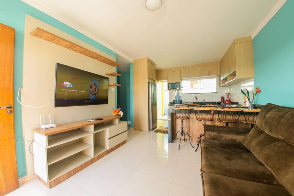 Il comprend une cuisine avec un canapé et une télévision murale. dans l'établissement Casa de veraneio a 2km da praia, à Porto Seguro