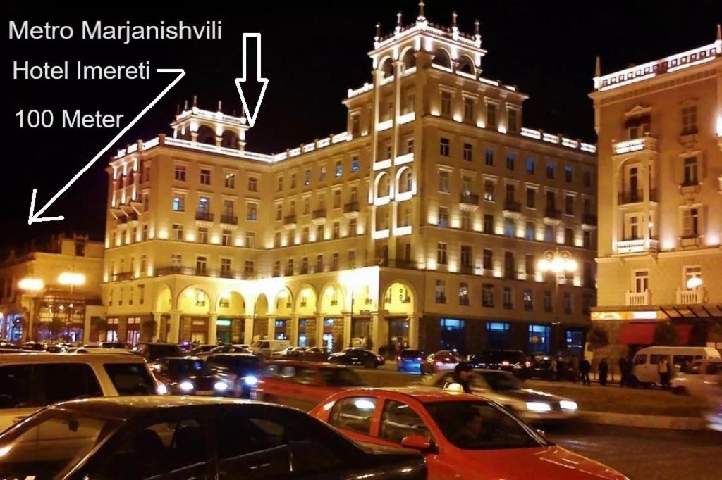 un gran edificio con coches estacionados frente a él en HOTEL IMERETI TBILISi en Tiflis