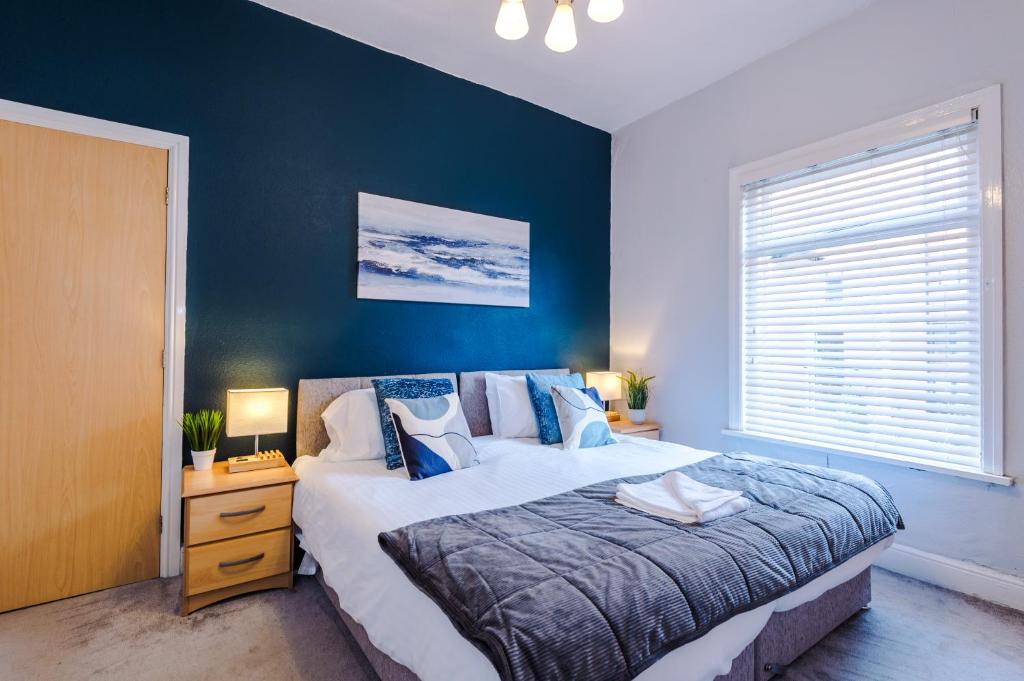 1 dormitorio con 1 cama grande y pared azul en Queens Avenue - Central Chester Home - Sleeps 9 en Chester