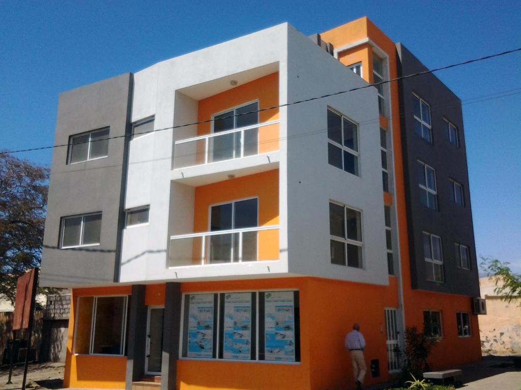 un edificio blanco y naranja con un hombre parado frente a él en Vannimar Lounge en Porto Novo