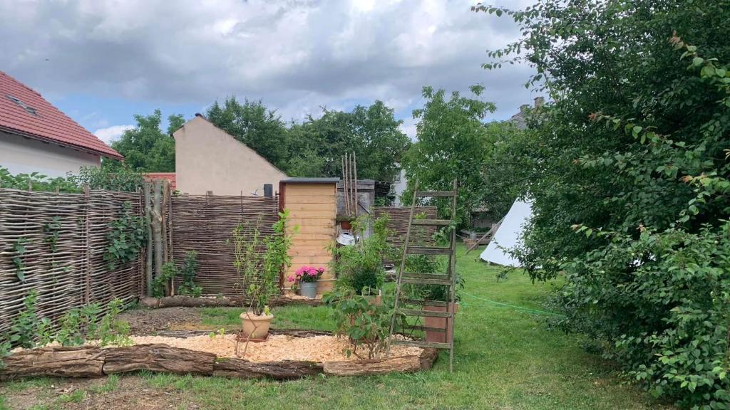 un jardin avec une clôture en bois et une échelle dans l'établissement TeePee OPPIDUM Praha-MotoFamily, à Lhota