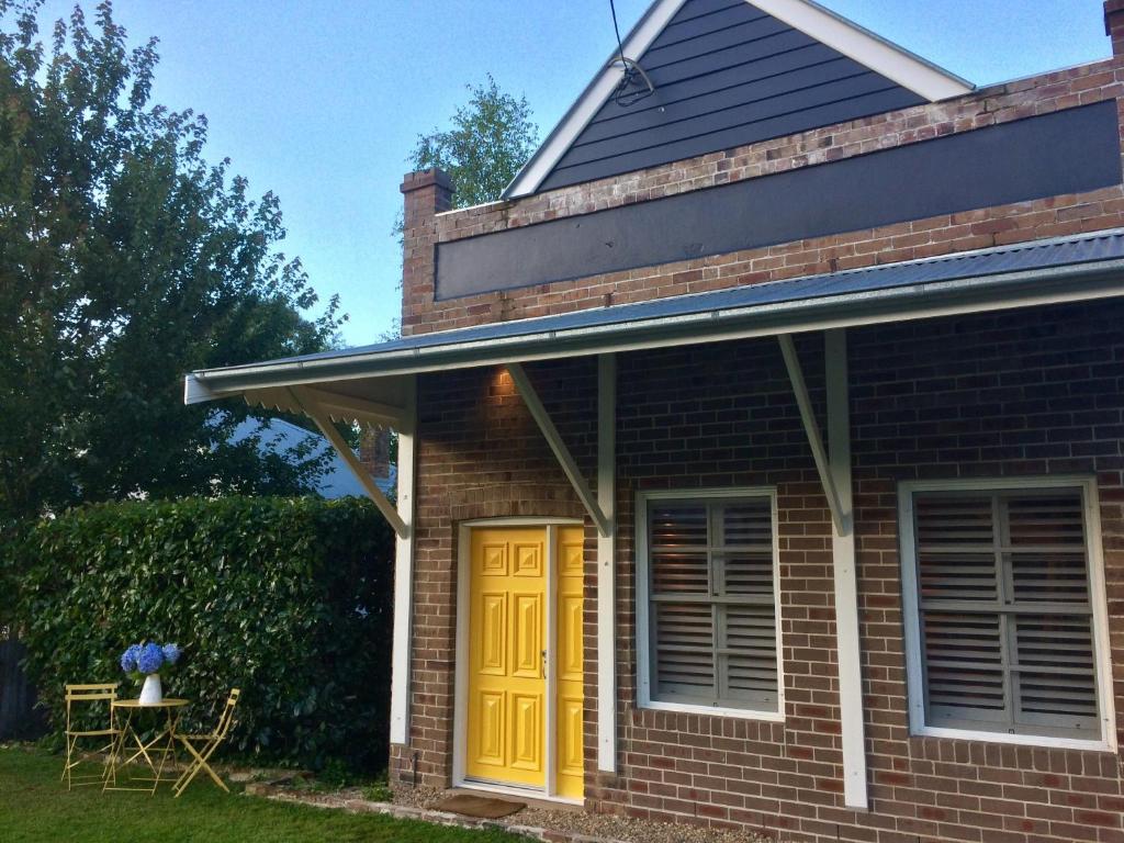 una casa de ladrillo con puerta amarilla en Bundanoon Bijou Southern Highlands Accommodation, en Bundanoon