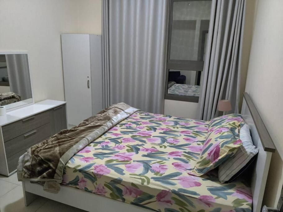 Schlafzimmer mit einem Bett, einer Kommode und einem Spiegel in der Unterkunft Lovely 2Bhk Family Apartment in Ajman in Al Ḩamīdīyah