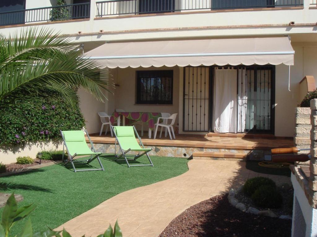 a patio with two green chairs and a table at Llevant 3 in L'Ampolla