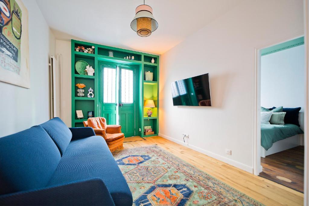 - un salon avec un canapé bleu et un lit dans l'établissement 2 pièces à Bastille, à Paris