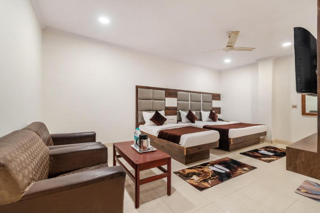 a bedroom with a bed and a couch and a television at Hotel South Indian in New Delhi
