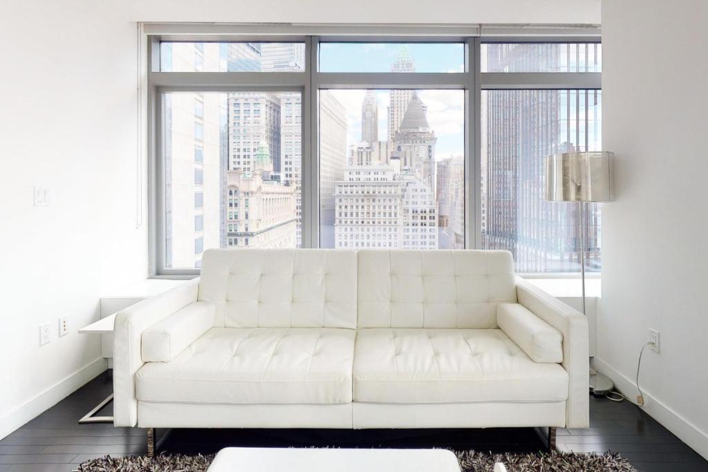 a white couch in a living room with a large window at Blueground Tribeca roof deck nr WTC NYC-1377 in New York