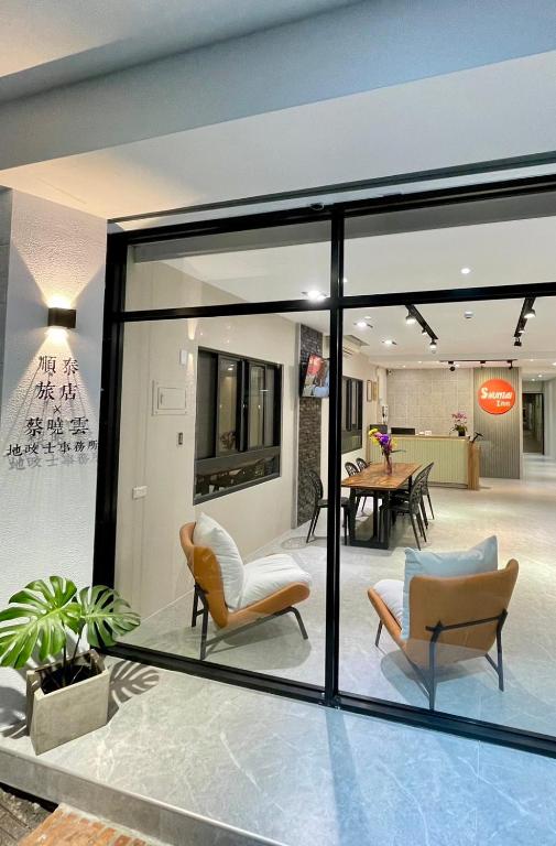 a glass extension of a building with chairs and a table at Shuntai Inn in Fengshan