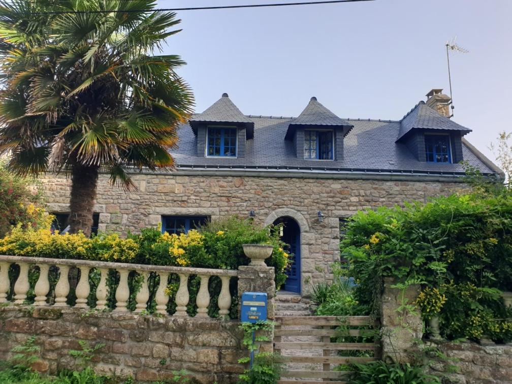 uma antiga casa de pedra com uma palmeira e uma cerca em la balinade em Riantec