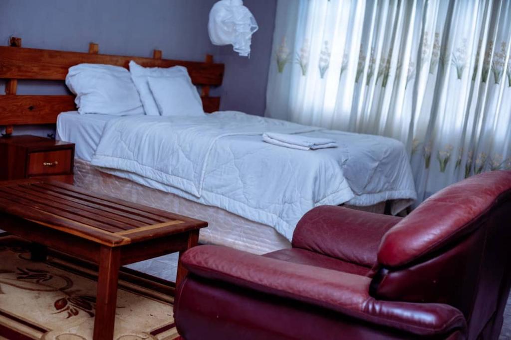 ChongweにあるWhite Lotus Lodges Kateteのベッドルーム1室(ベッド1台、椅子、ソファ付)