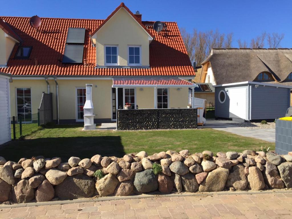 una casa blanca con techo rojo y un montón de rocas en Ferienhaus Meerik für 6 Personen mit Sauna, Terrasse und Kamin, en Rerik