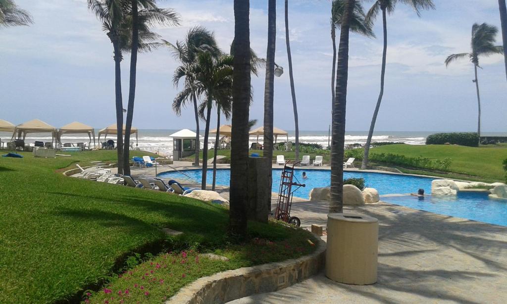 una piscina con palmeras y la playa en Mayan Vidanta PLAYA departamento REMODELADO 2 y 3 recámaras, en Acapulco