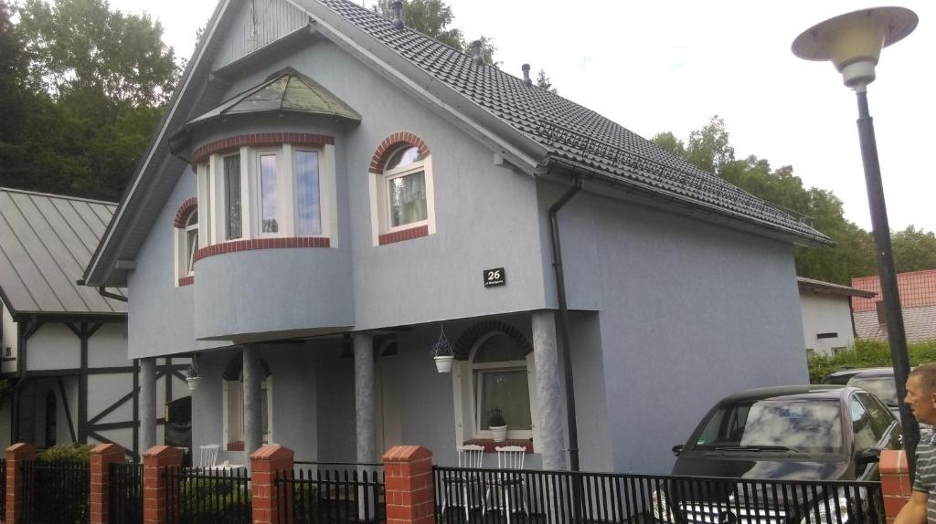 a small house with a black fence in front of it at Dom Lidia in Poddąbie