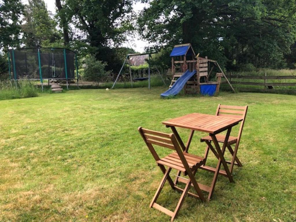un tavolo da picnic e una panca in un cortile con parco giochi di Gîte au Calme tout équipé a Cléguérec
